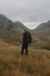 Man with backpack hiking in autumn Scottish Highlands