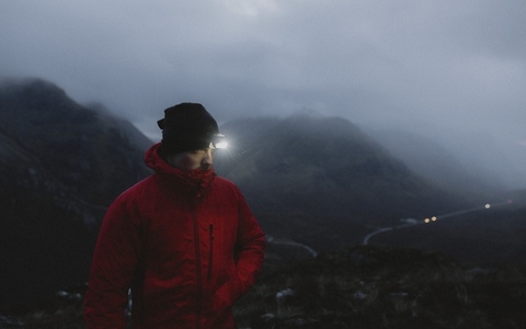 Male hiker with headlamp in foggy Scottish Highlands