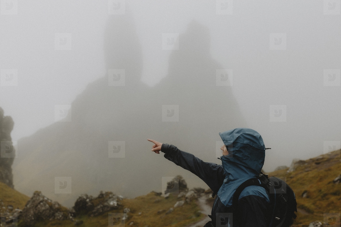 Man Ran Way Pattern Man in ran jacket hiking below foggy Old Man of Storr rock formation ...