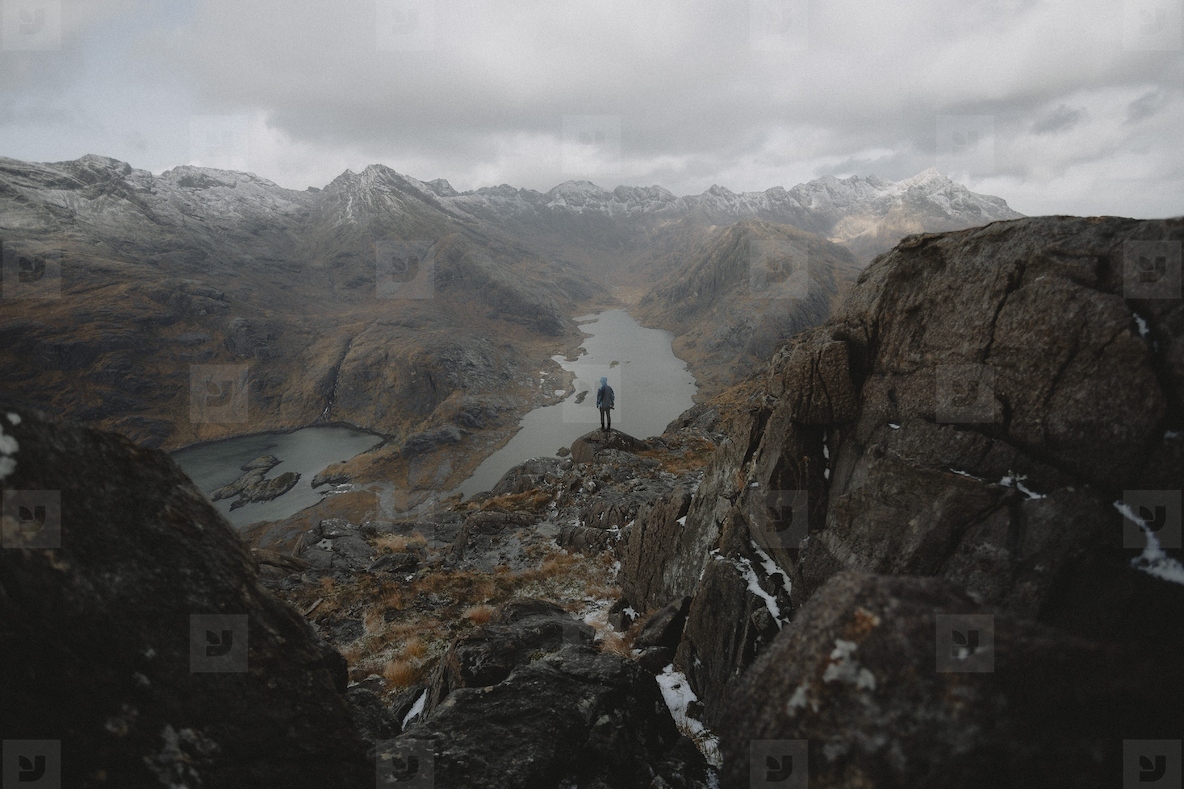 Hiker on rugged rocks overlooking majestic mountain range view