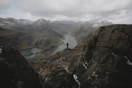 Hiker on rugged rocks overlooking majestic mountain range view