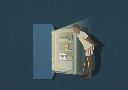 Man standing at open refrigerator in kitchen at night