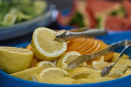Close up fresh lemon and orange slices in bowl with tongs