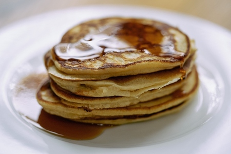 Close up stack of pancakes with maple syrup on plate