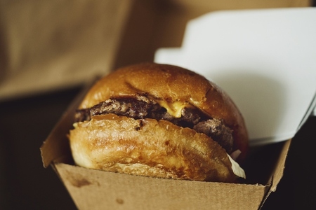 Close up takeout hamburger on brioche bun in container