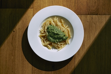 Still life pasta with pesto sauce in bowl on sunny table