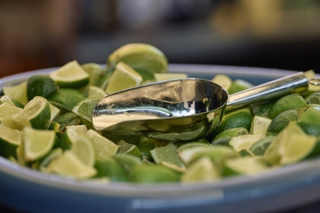 Close up fresh lime wedges in bowl with scoop