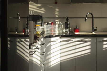 Sunlight and reflections casting shadows in apartment kitchen