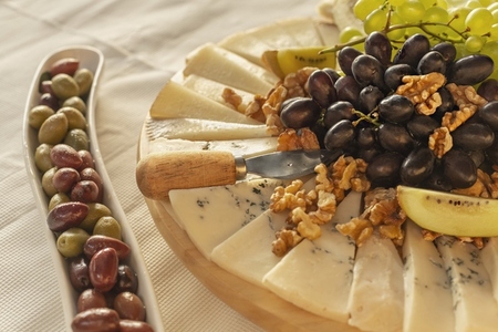 Still life olives and cheese board with grapes and walnuts