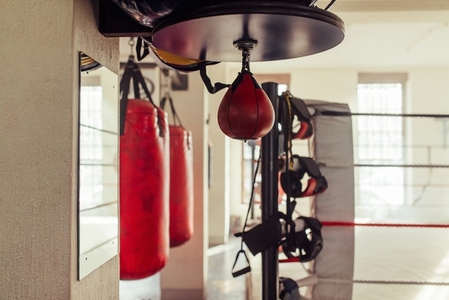 Small red punching bag hanging near other equipment in a boxing gym