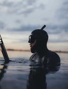 Underwater hunter spearfishing in the sea at sunset