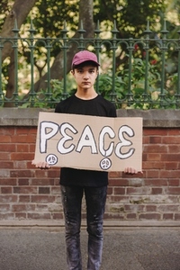 Teenage boy holding a peace poster outdoors