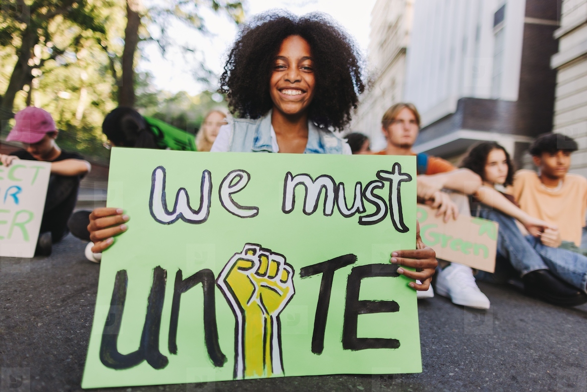 Cheerful black girl holding a poster at a climate protest