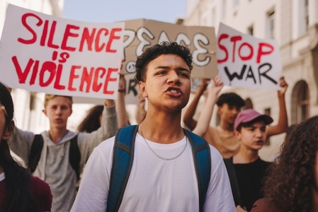 Teenage boy marching against war with a group of protestors