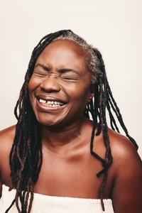 Joyful mature woman laughing happily in a bath towel