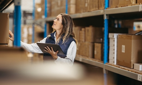 Female warehouse manager counting stock using a digital tablet