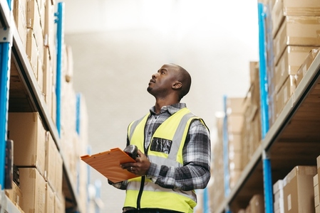 Young logistic supervisor checking package details in a warehouse