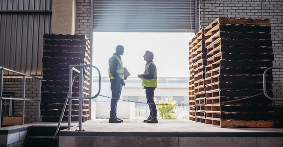 Two warehouse logistics workers talking on a loading bay