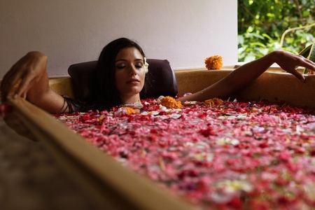 Beautiful woman in bathtub with flower petals