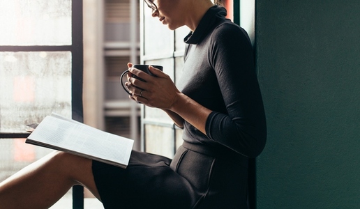 Woman reading a magazine and having coffee