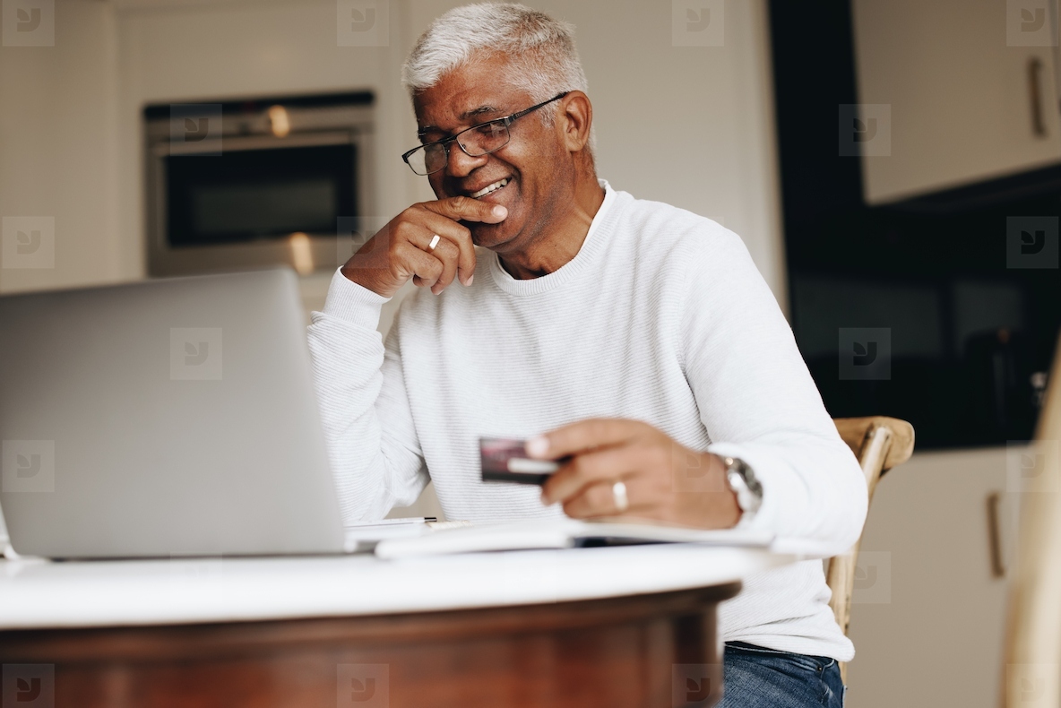 Carefree senior man shopping online at home
