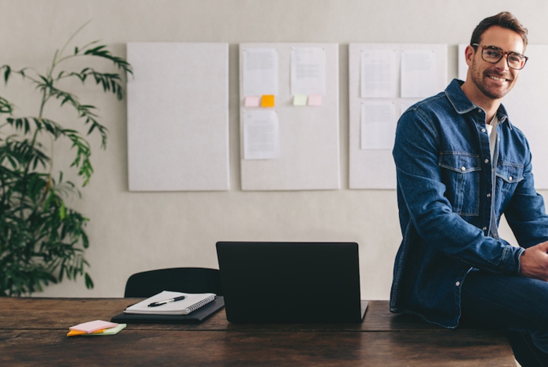 Successful businessman smiling at the camera while holding a smartphone