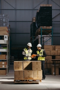 Logistics employees reading a clipboard in a warehouse