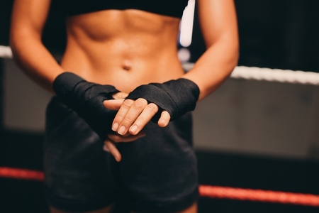 Female athlete wrapping her hands in a boxing ring