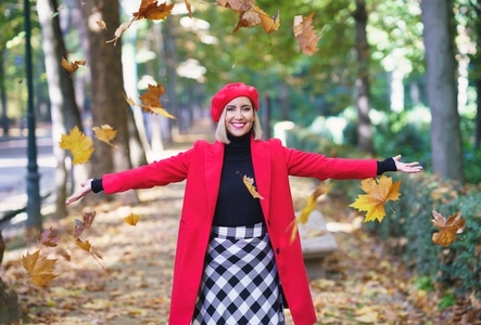 Happy woman throwing autumn leaves in park