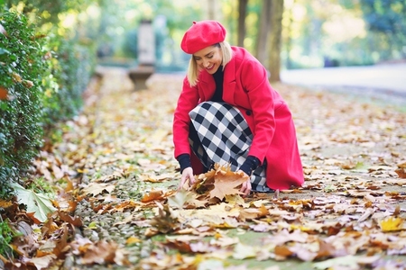 Smiling woman picking autumn leaves from ground