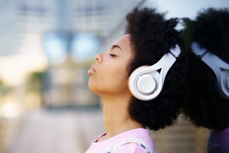 Black woman listening to music on street