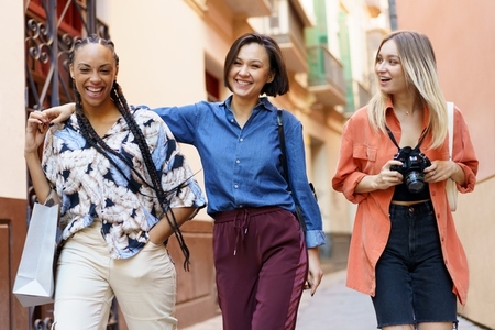 Multiracial females laughing during stroll near building