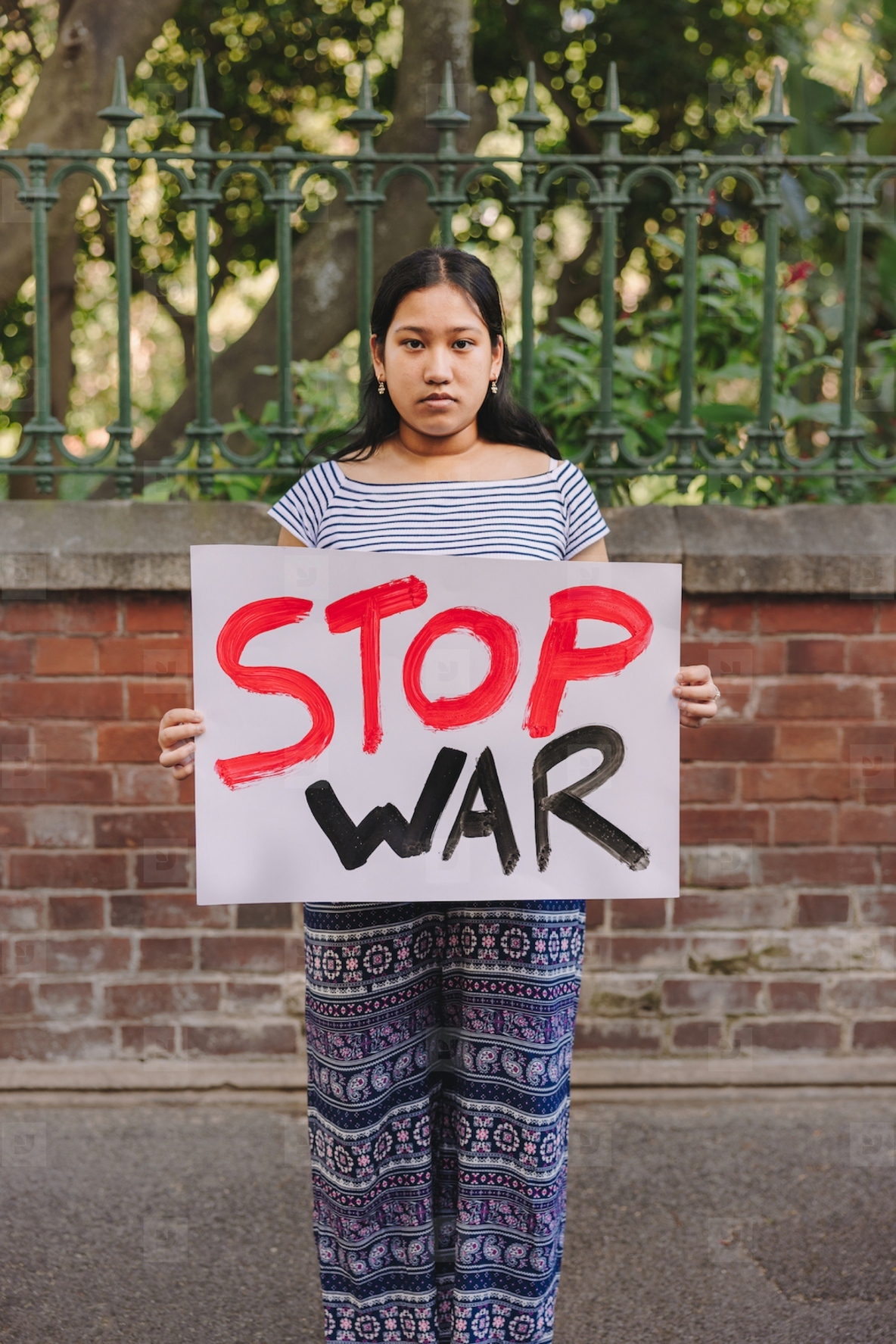 Ethnic girl holding an anti war poster outdoors