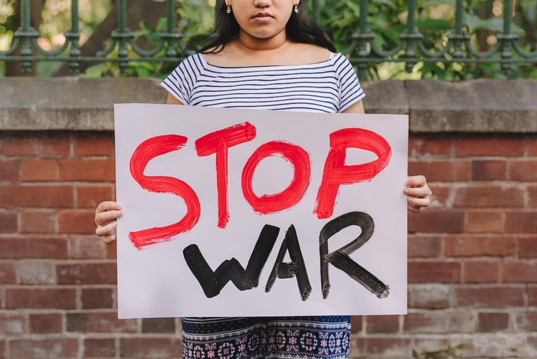 Ethnic girl holding an anti-war poster outdoors