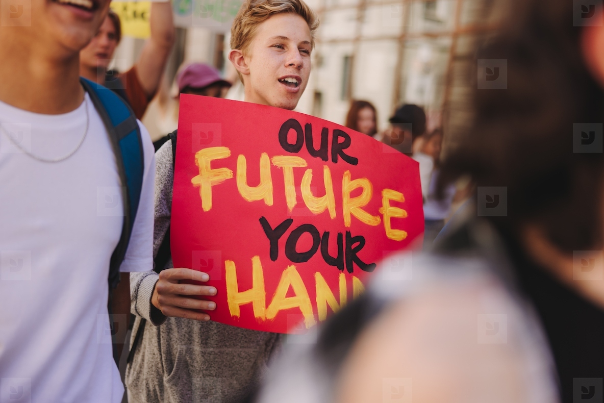 Teenage boy holding a banner during a climate change protest