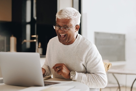 Cheerful senior businessman having an online meeting at home