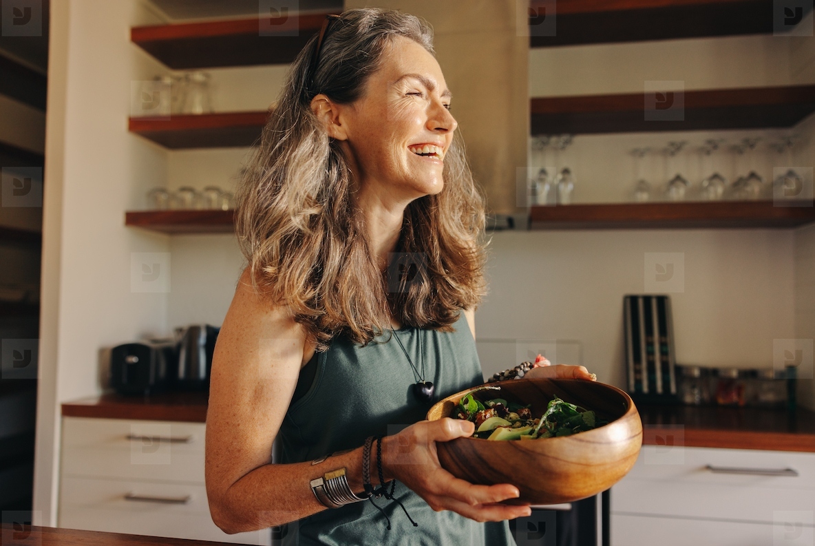 Aging woman smiling happily while holding a buddha bowl