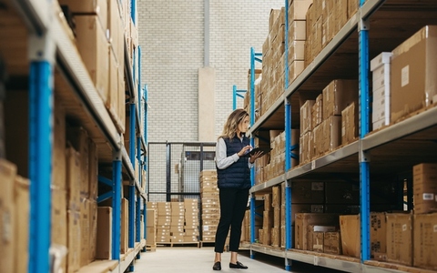 Female warehouse worker doing inventory control using warehouse management software