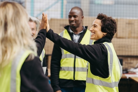 Warehouse workers high fiving each other