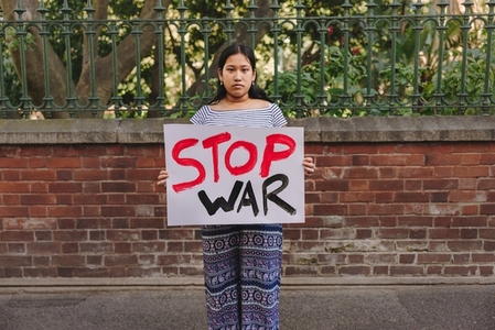 Teenage girl holding an anti war poster outdoors