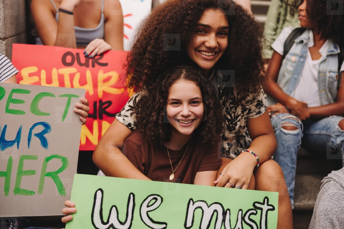 Cheerful teenage girls sitting with a group of climate activists