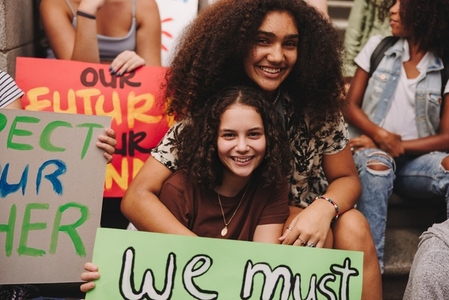 Cheerful teenage girls sitting with a group of climate activists