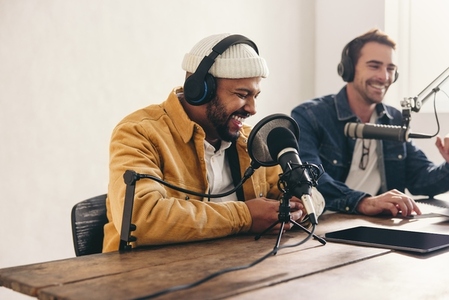 Two college podcasters having a good time in a studio