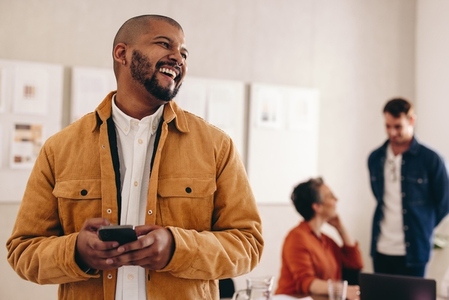 Happy businessman with a septum ring holding a smartphone