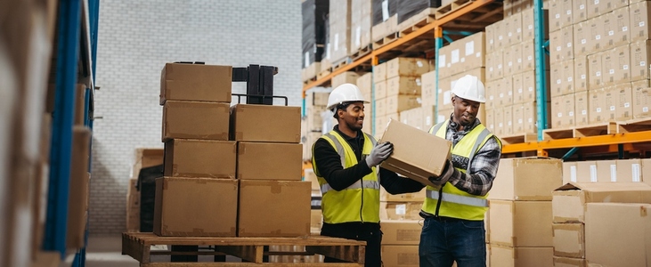 Male warehouse workers offloading packages from a pallet truck