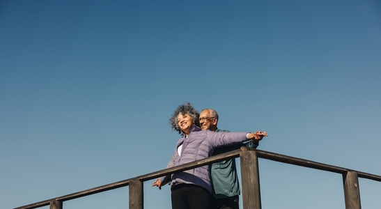 Cheerful senior couple having fun on a wooden foot bridge