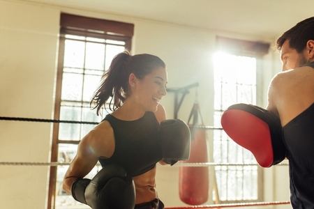 Happy female boxer sparring with instructor