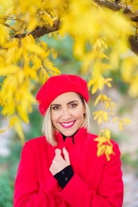 Excited graceful female smiling in autumn park in sunlight