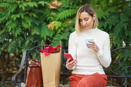Woman browsing smartphone on bench near flowers