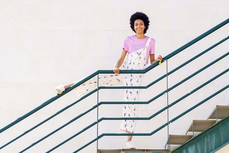 Cheerful black woman standing on stairway